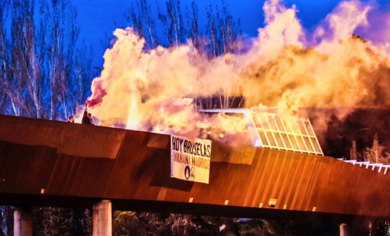 Bengalas ardiendo y una pancarta en la que pone: "Hoy Bruselas, ¿mañana Madrid?", obra del grupo Hogar Social Madrid, junto a la mezquita de la M-30.