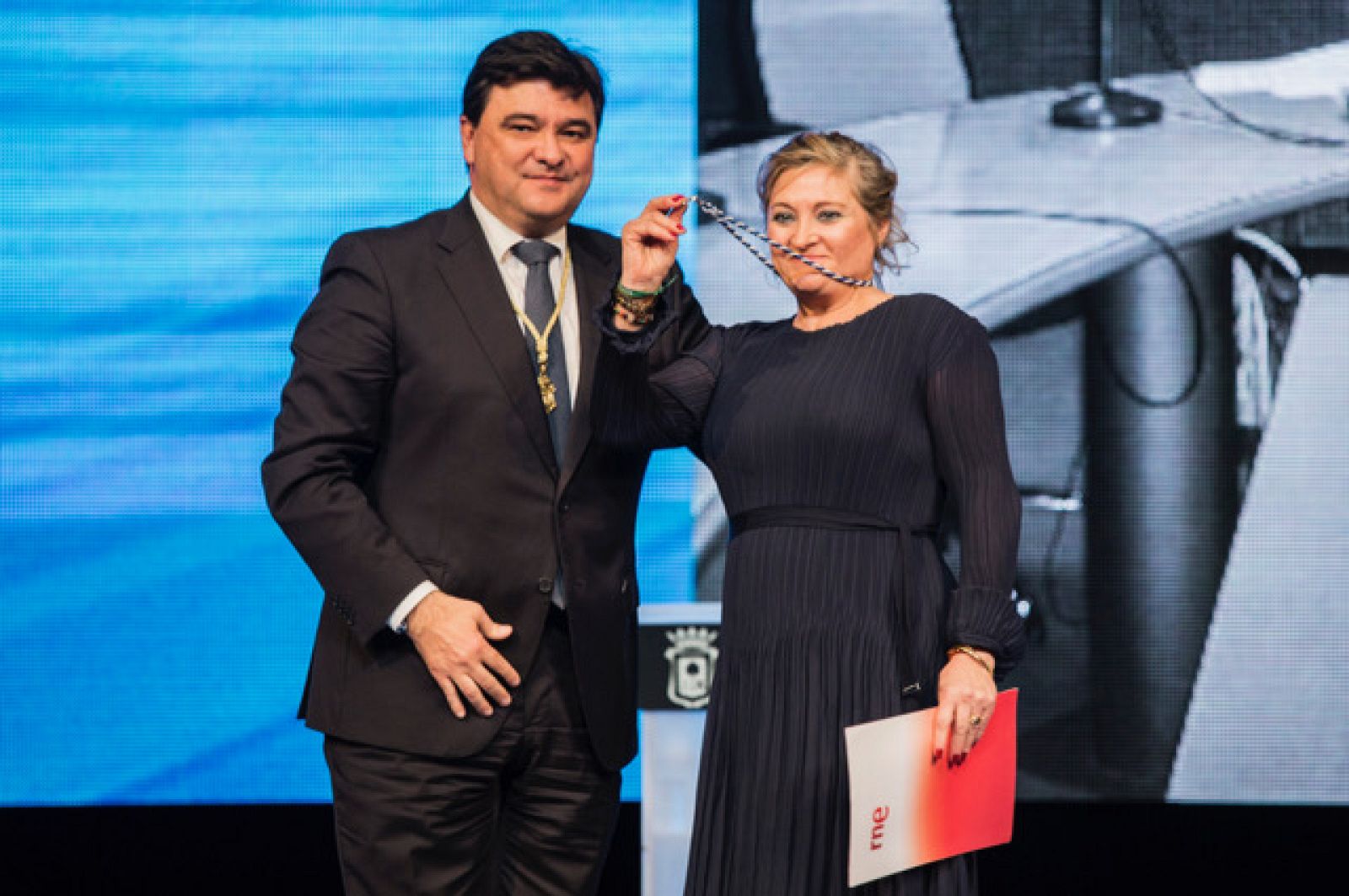 Ernestina Ferrer, de RTVE Huelva, recoge la medalla de manos del alcalde de la ciudad