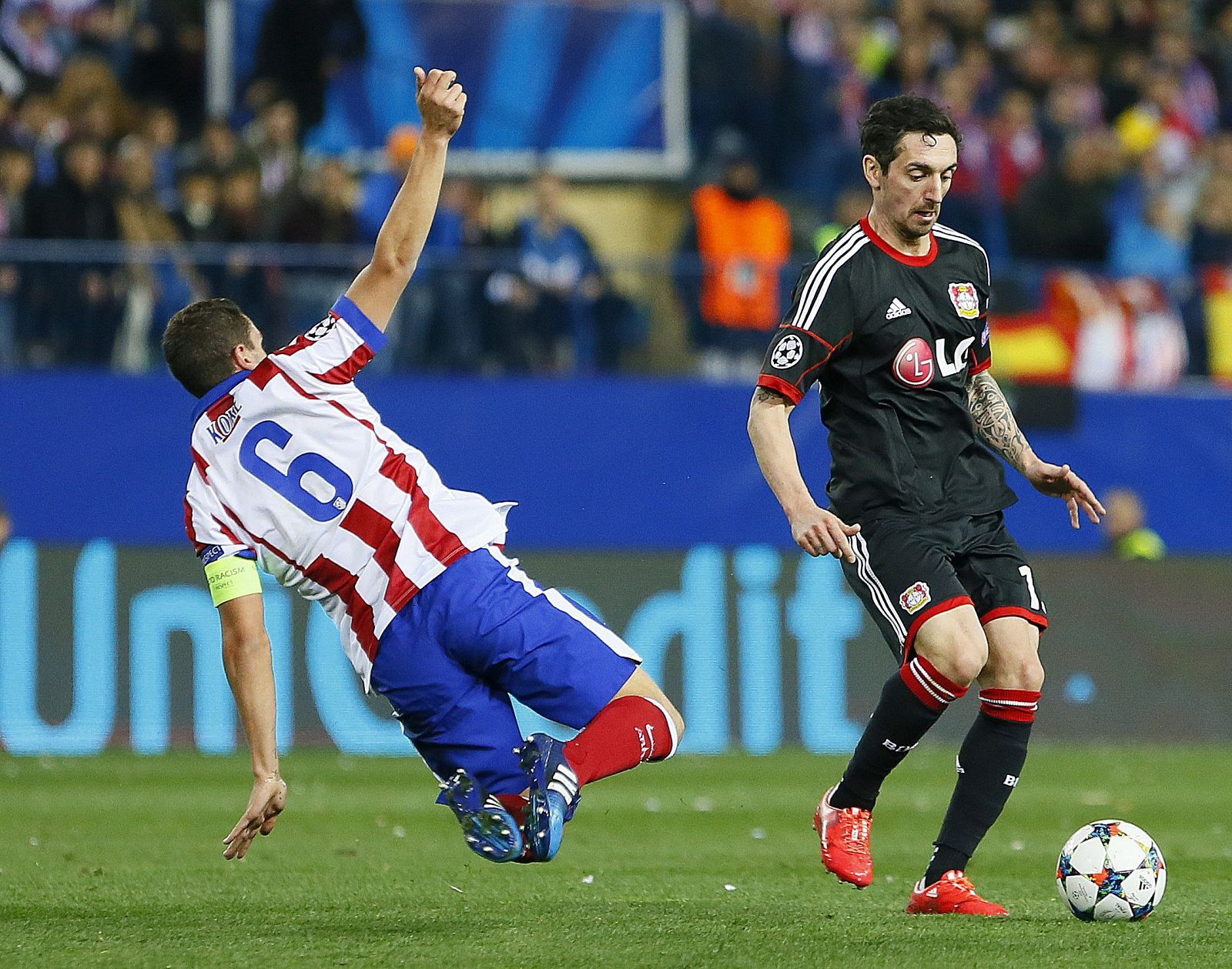 Hakan Calhanoglu (d) con el balón ante Koke Resurrección (i) durante partido de vuelta de octavos de final de la Liga de Campeones.