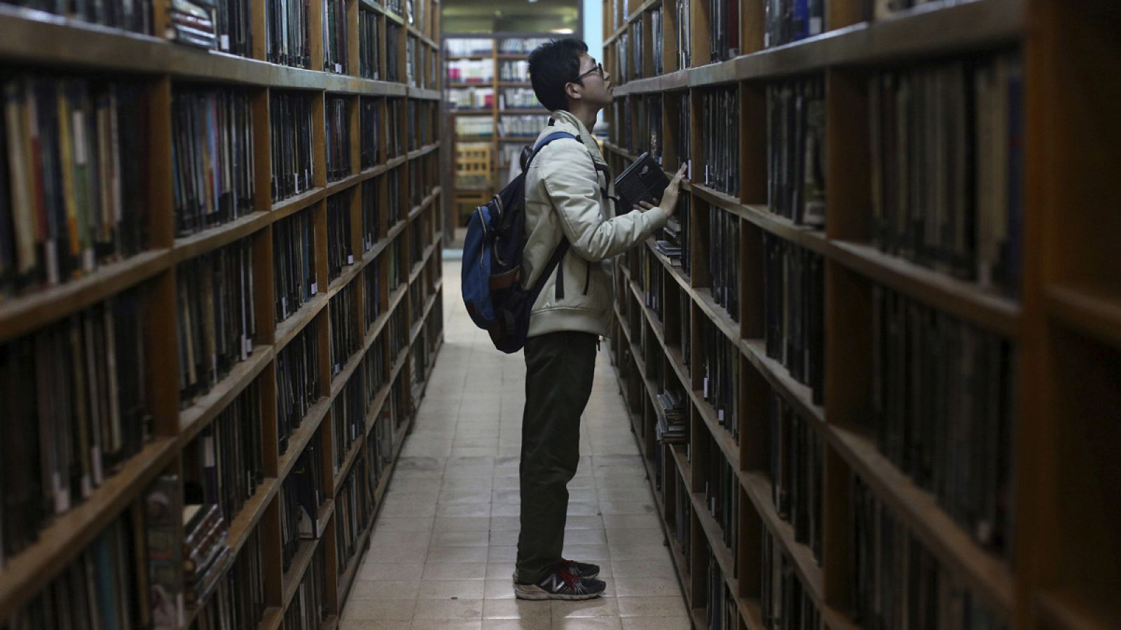 Imagen de un joven buscando libros en una biblioteca.