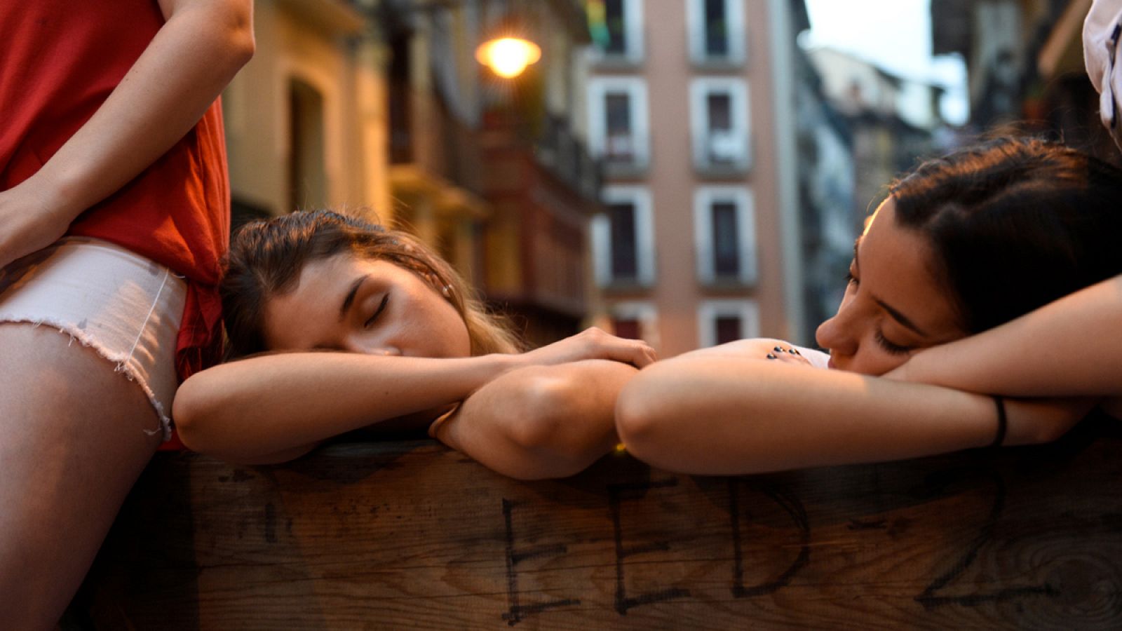 Dos chicas jóvenes duermen contra la valla antes del segundo encierro de San Fermín de 2017