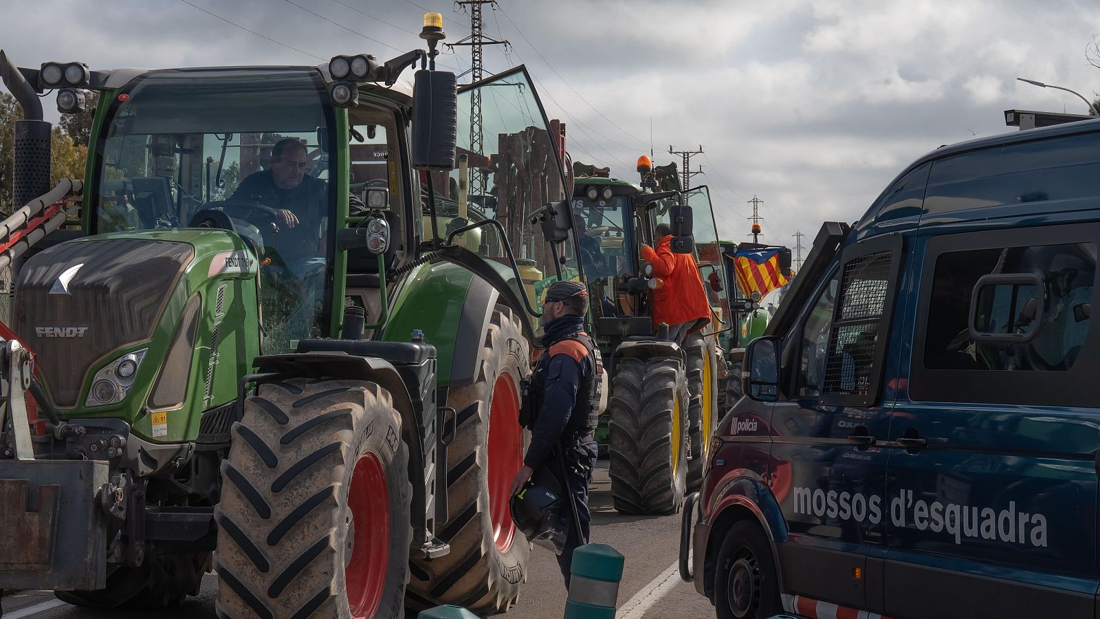Un agente de los Mossos d'Esqueadra habla con un agricultor en uno de los accesos a Mercabarna