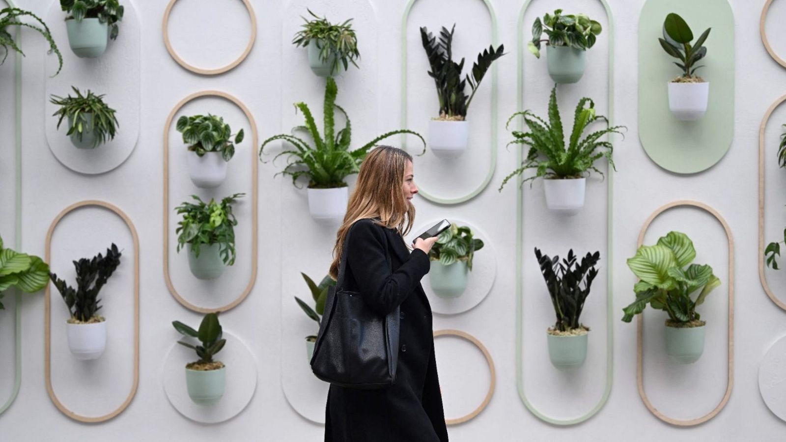 Una visitante pasea por el Mobile World Congress (MWC) con su dispositivo mòvil.