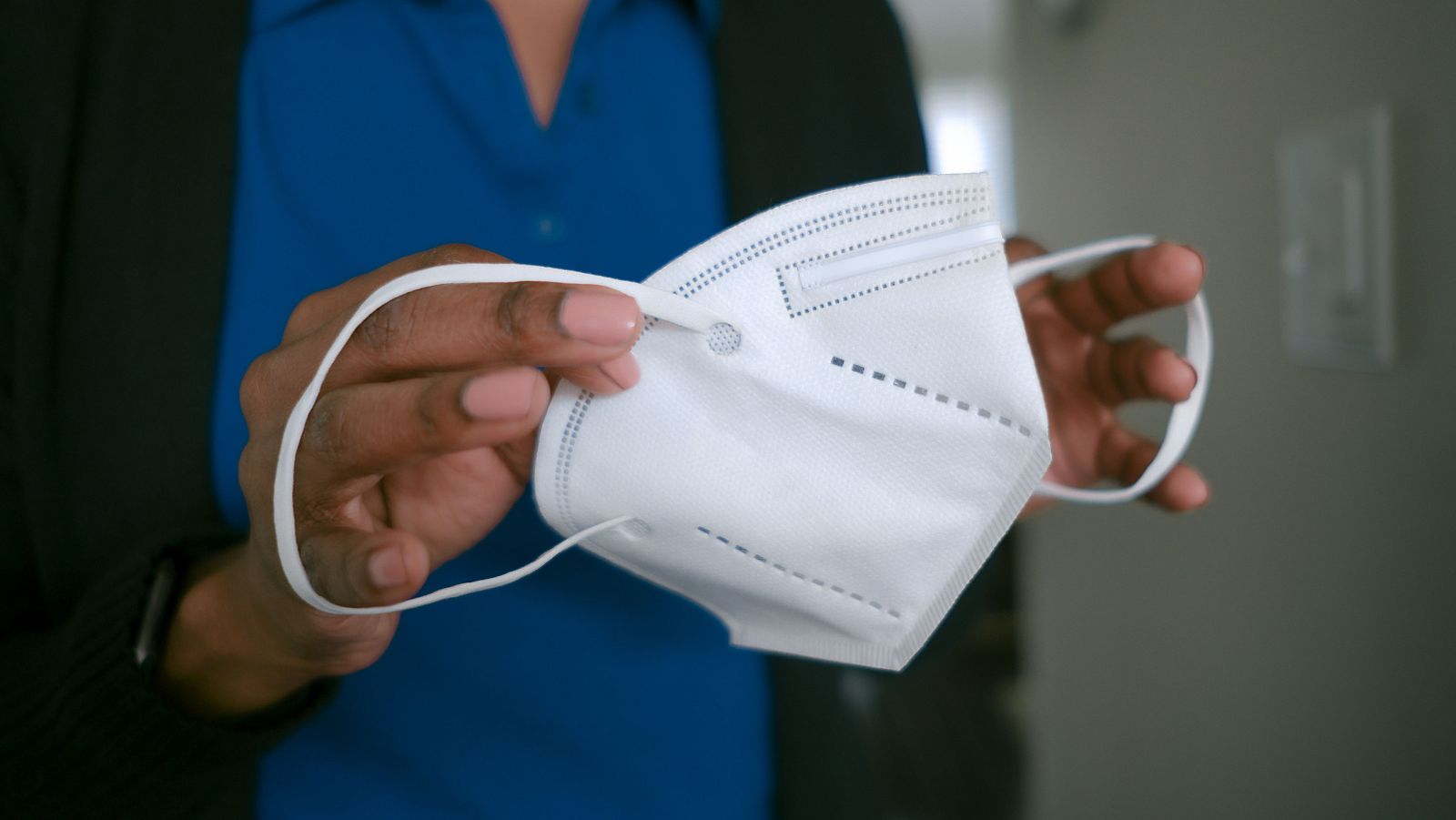 Una mujer se pone una mascarilla