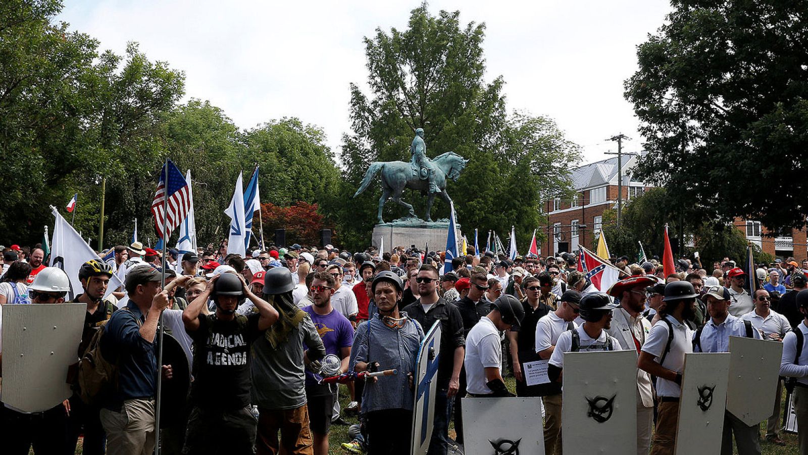 Imagen de la concentración racista frente a la estatua del general confederado Robert E. Lee en Charlottesville, Virginia. Los manifestantes portan banderas, escudos y símbolos de varios grupos de extrema derecha.