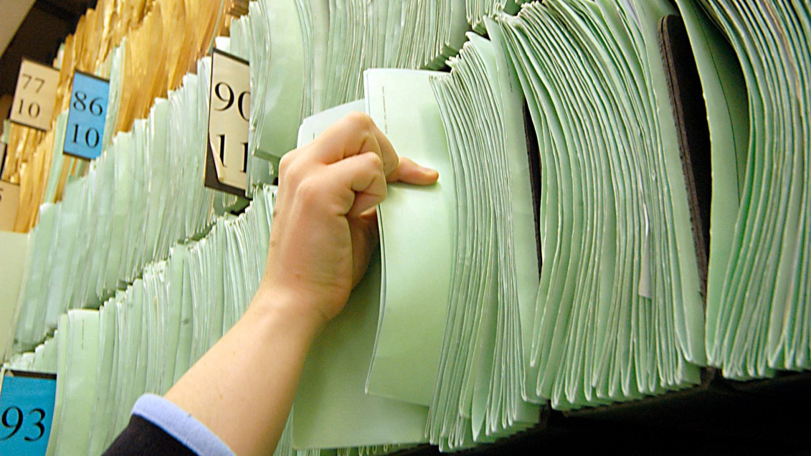 Una funcionaria coge un expediente para consultarlo