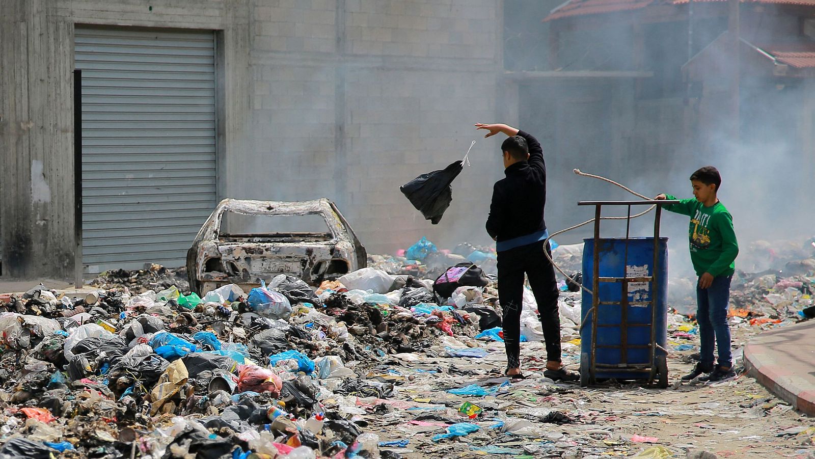 Dos niños buscan entre la basura en una calle de Gaza