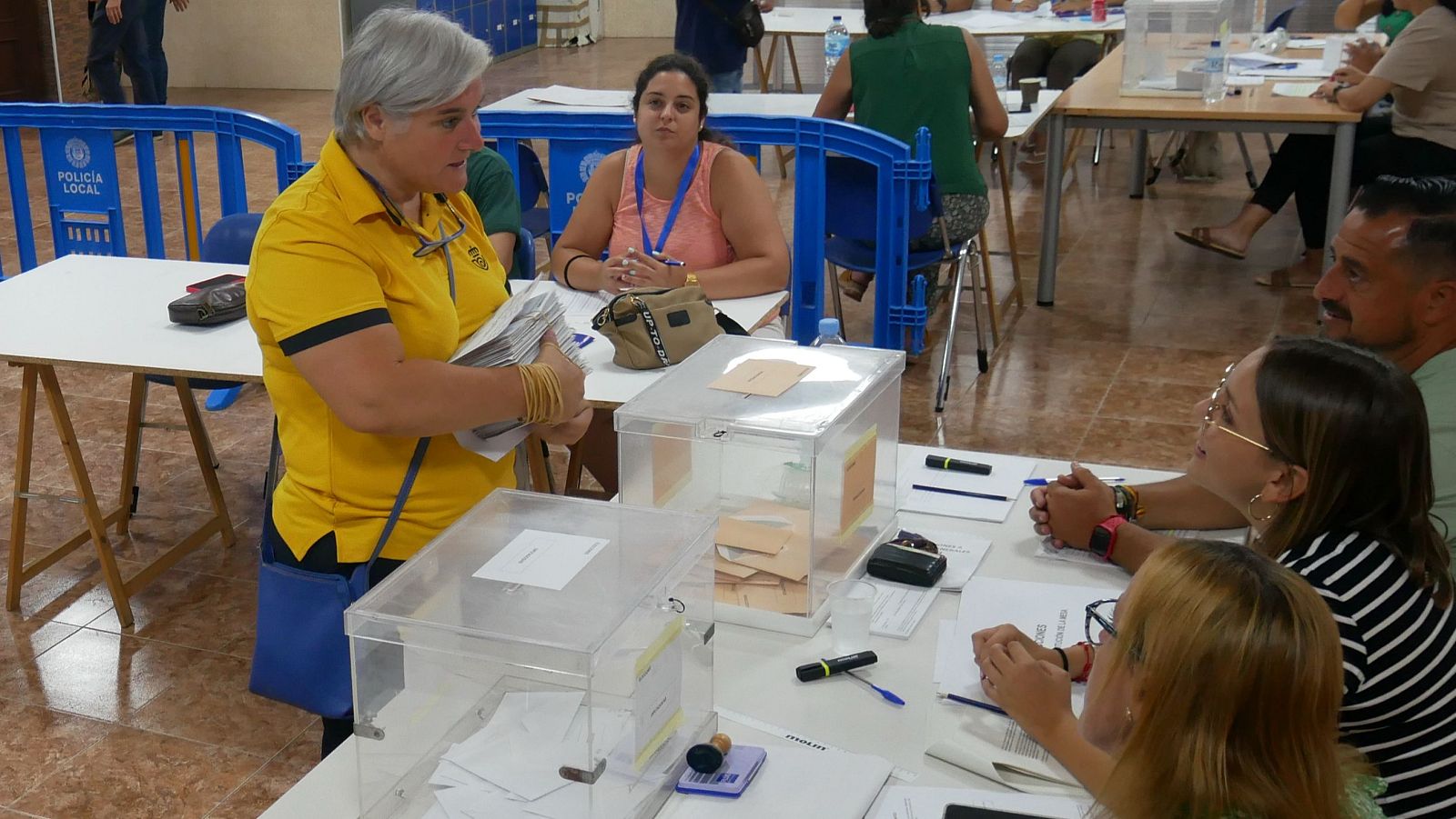 Una funcionaria de Correos entrega los votos por correo en una mesa electoral.
