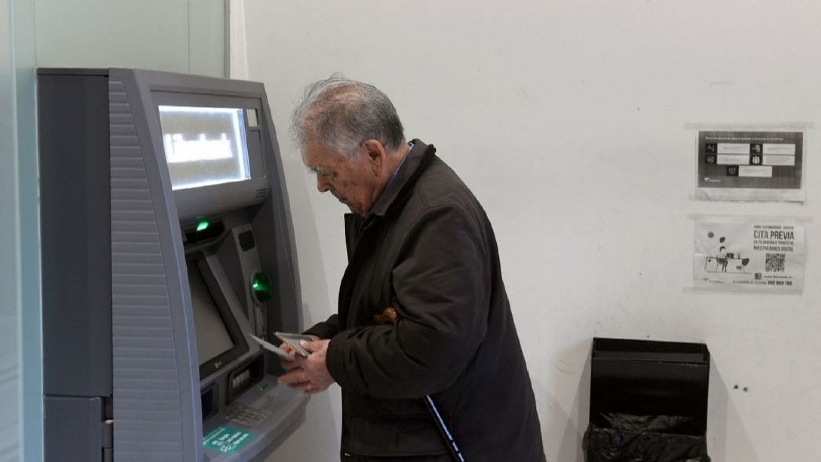 Señor mayor intentando hacer gestiones en el cajero automático