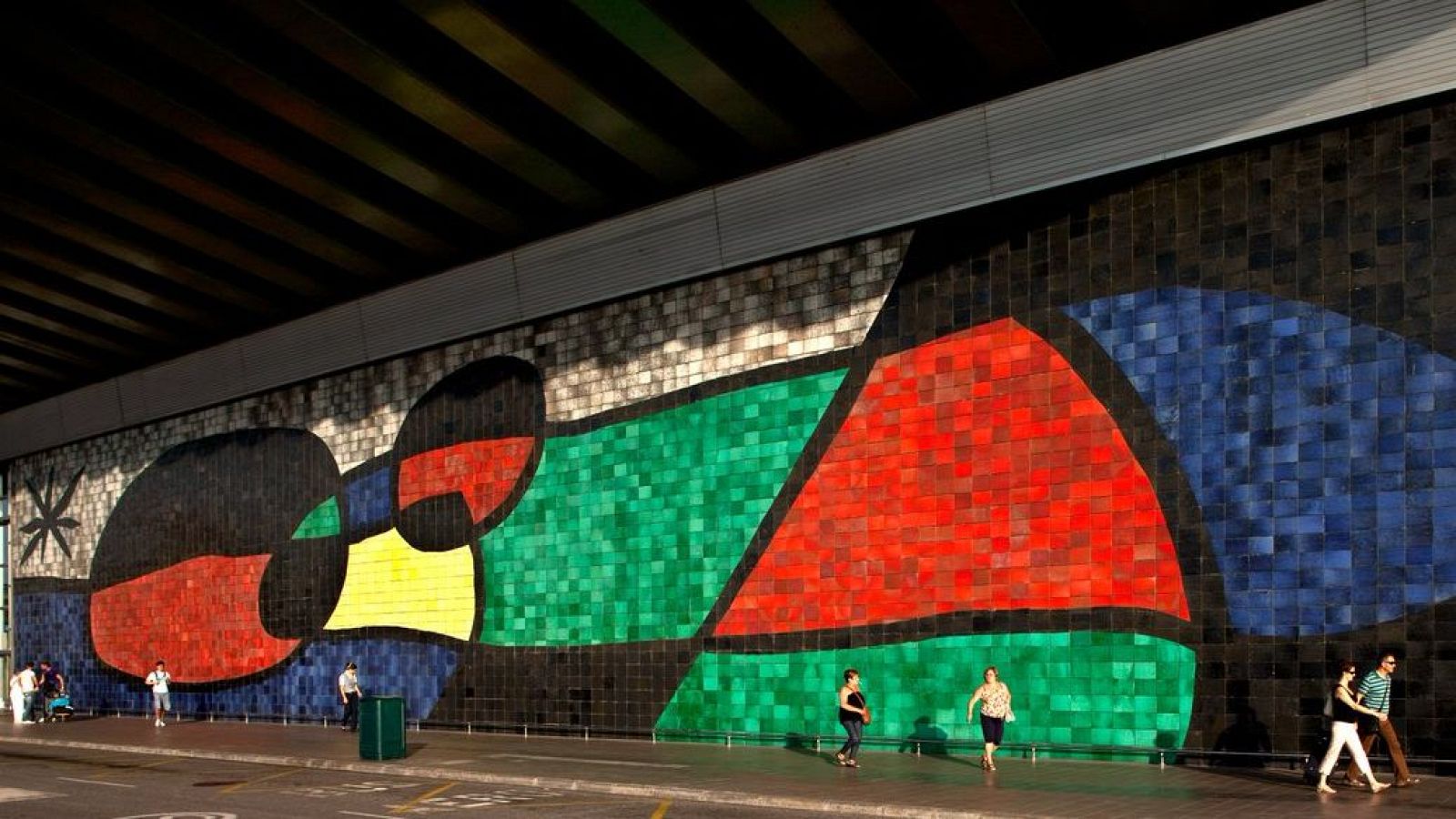 Vibrante mosaico mural abstracto de Miró en el Aeropuerto del Prat. Colores brillantes y formas características del artista. Gran tamaño, visible desde la calle.