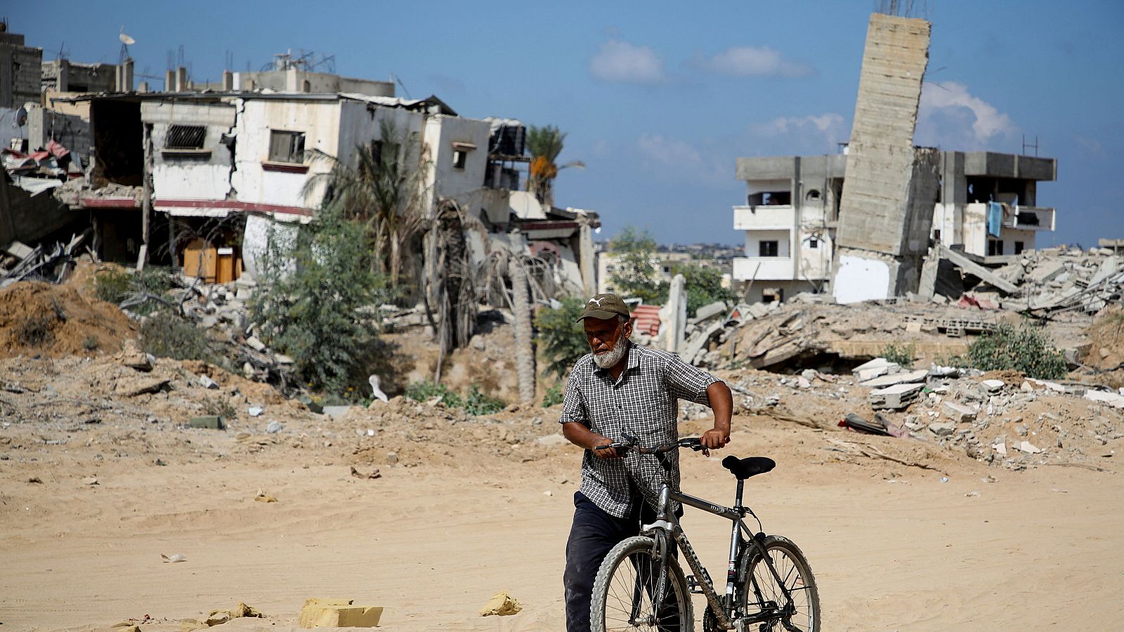 Un palestino camina con una bicicleta en Jan Yunis, después de que las fuerzas israelíes se retiraran de la zona.
