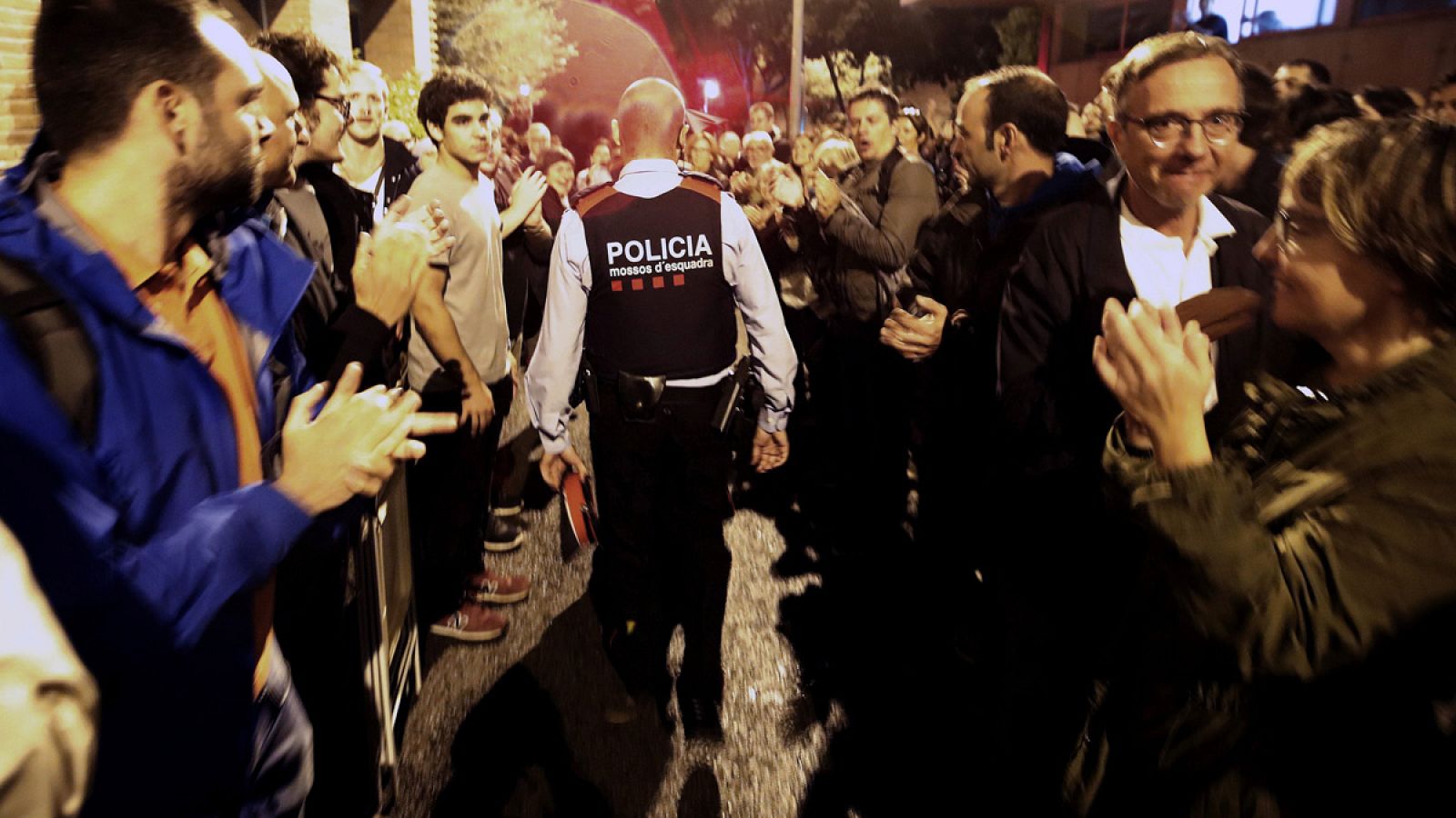 Una pareja de Mossos d'Esquadra salen entre aplausos de una escuela de Barcelona durante el 1-O