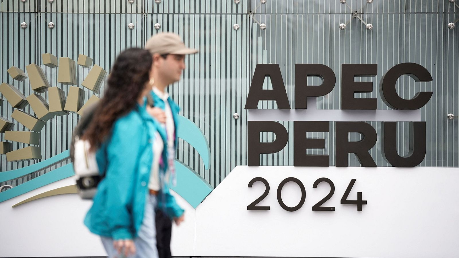Cartel anunciando la Cumbre APEC Perú 2024 con dos personas caminando en primer plano.