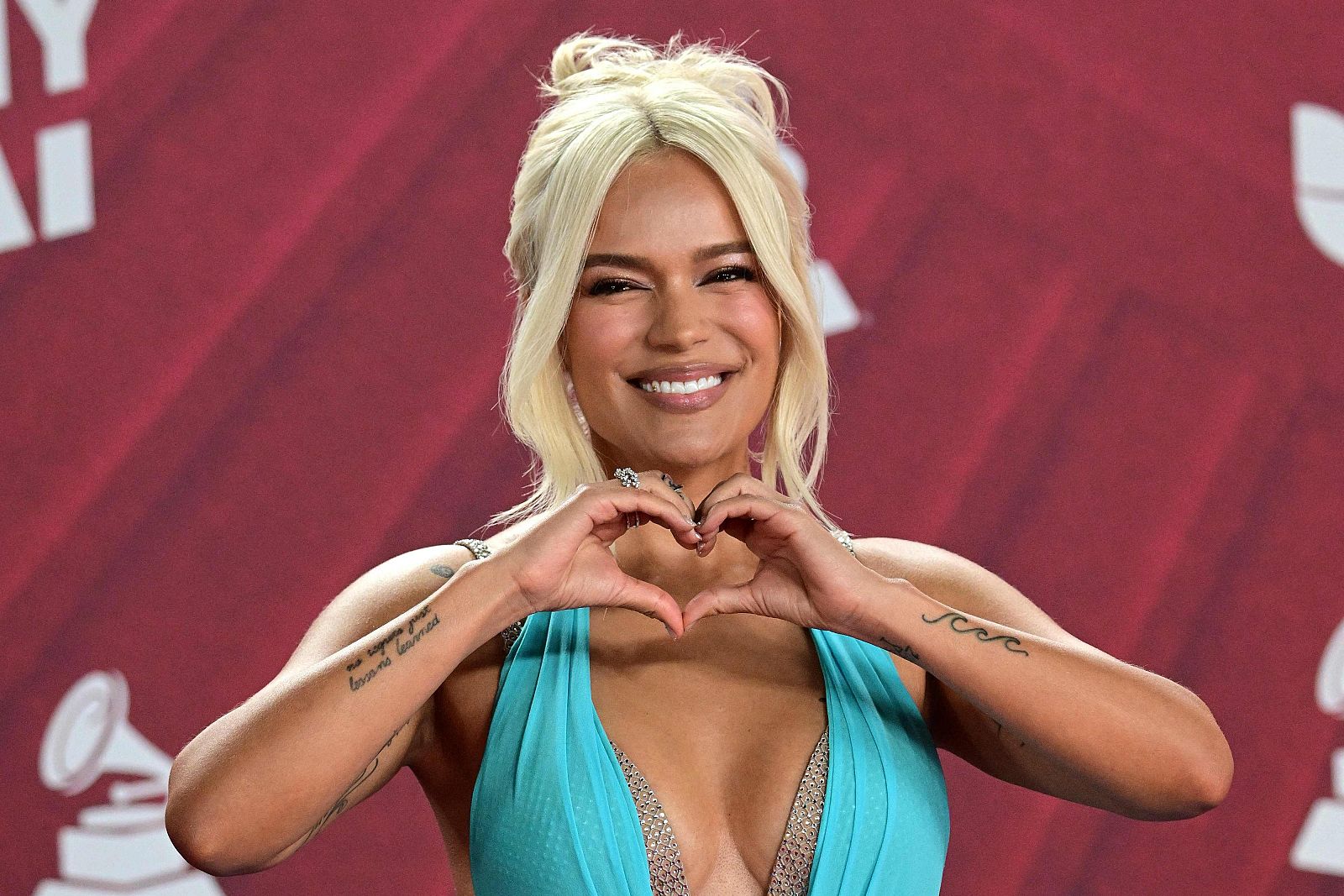 Karol G forma un corazón con las manos en la alfombra roja de los Latin Grammy.