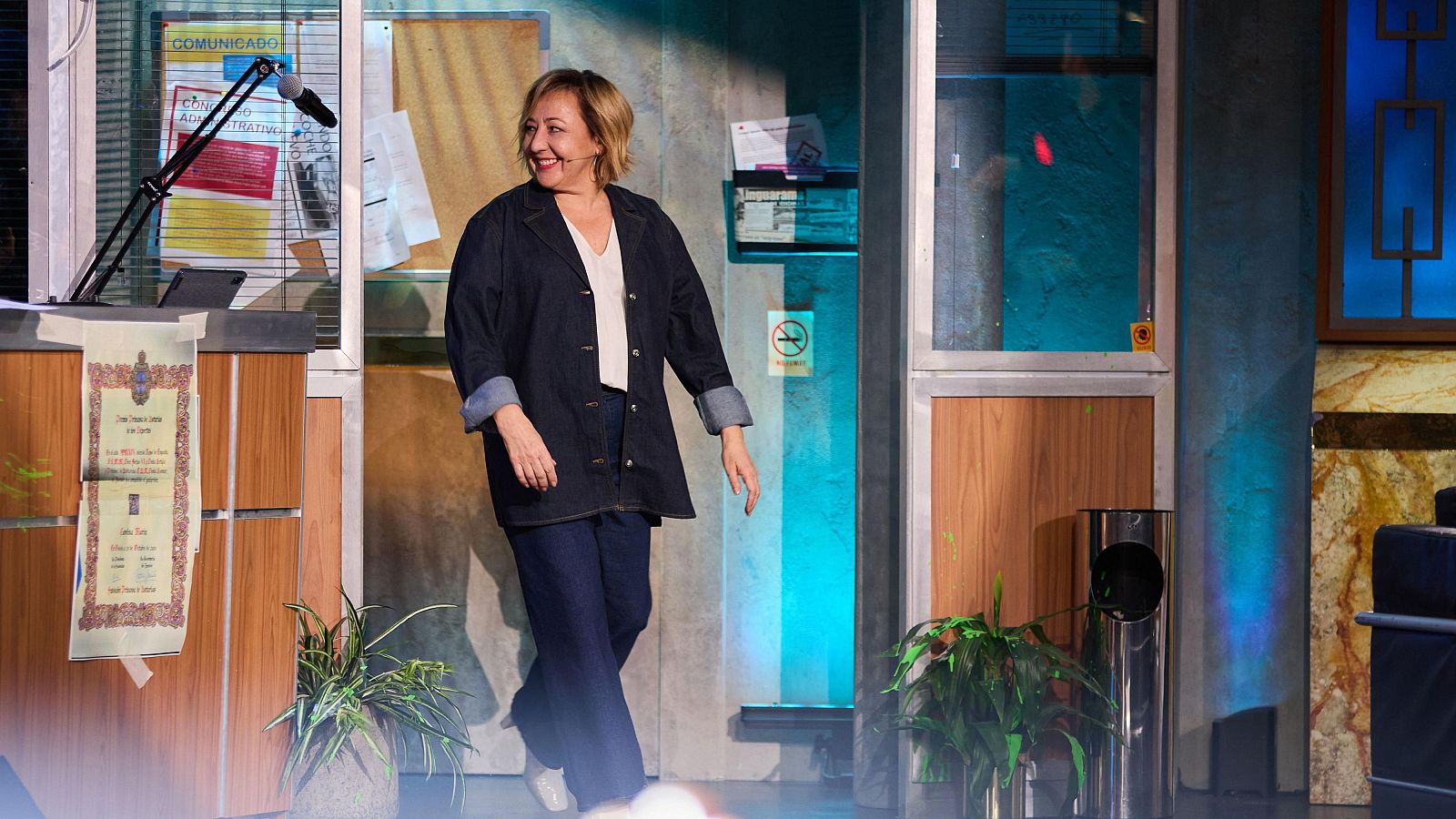 Carmen Machi visita el plató de La Resistencia con una sonrisa, vestida con una chaqueta vaquera y pantalones oscuros.