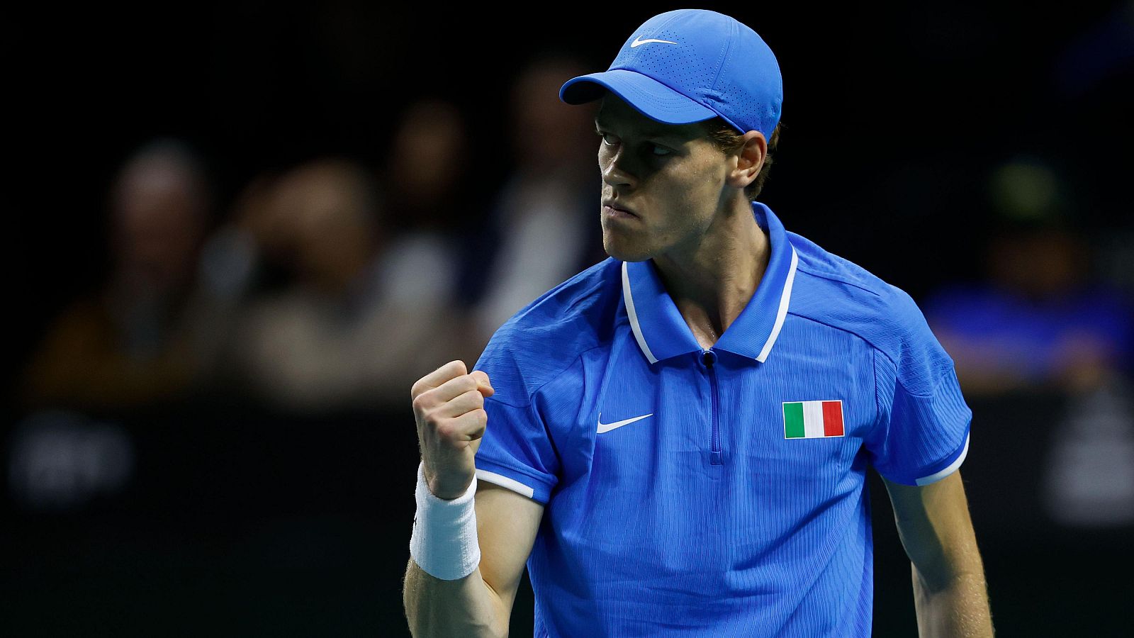 Tenista italiano celebrando un punto en la final de la Copa Davis contra Países Bajos. Lleva camiseta y gorra azules, muñequeras blancas y el logo de Nike.