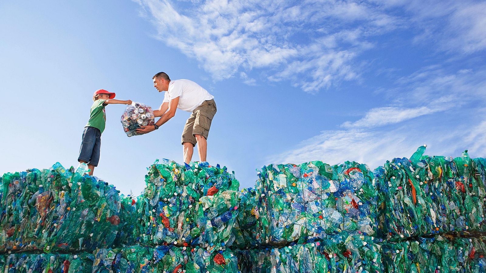 Hombre y niño reciclan botellas de plástico en un centro de reciclaje.  Acción cívica que contribuye a un récord europeo.