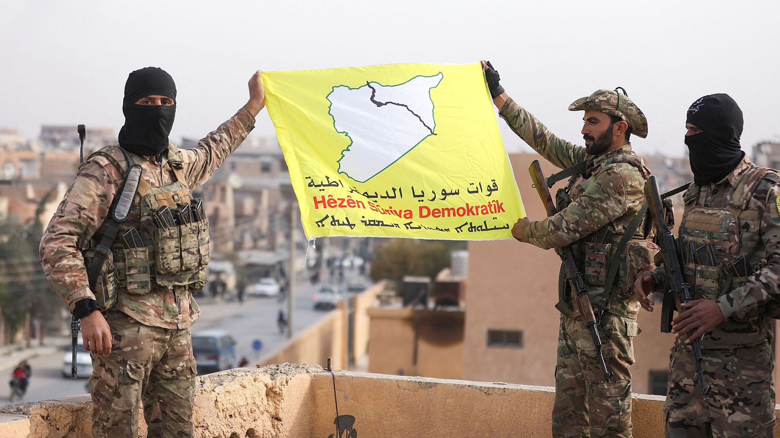 Miembros de las Fuerzas Democráticas Sirias (FDS) dirigidas por kurdos sujetan una bandera