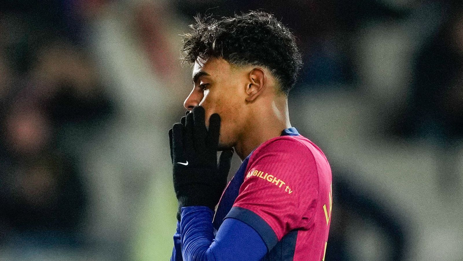Jugador de fútbol con camiseta del Barça y guantes Nike, mostrando una expresión de concentración o preocupación durante un partido.