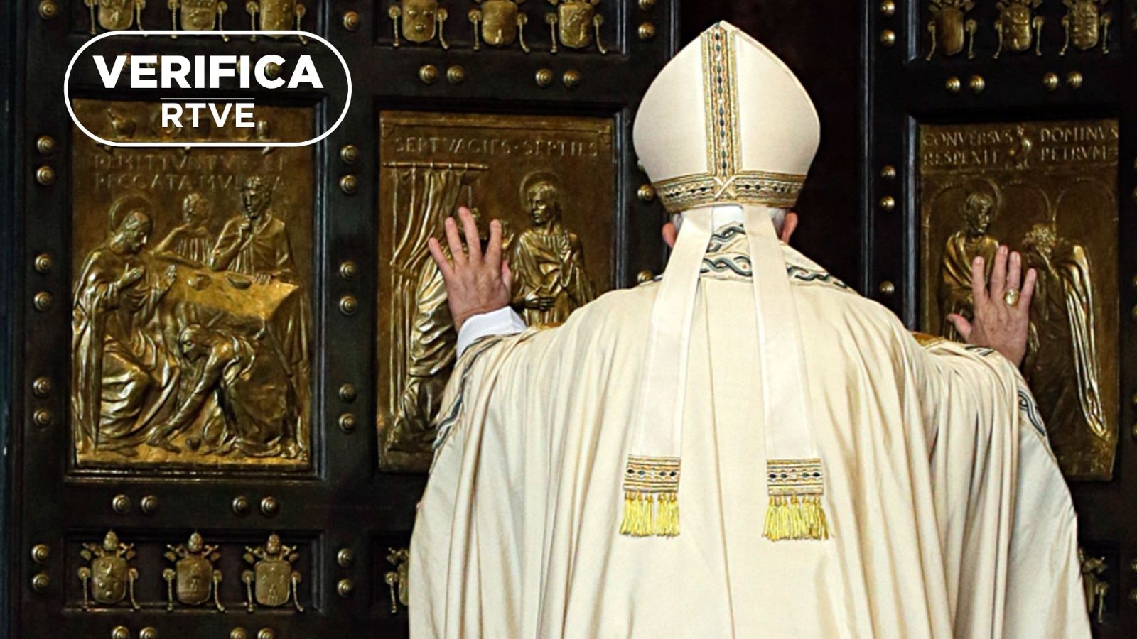 El Papa Francisco, con mitra y túnica blanca, frente a una puerta ornamentada con escenas religiosas. Imagen que refuta teorías conspirativas.