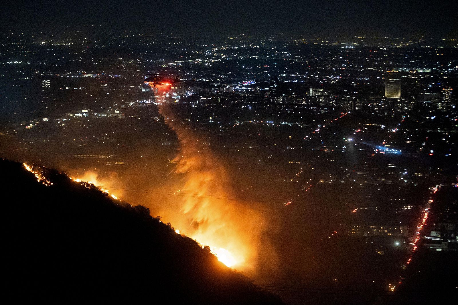 Un helicóptero virtiendo agua para apagar el fuego en Hollywood Hills (distrito de Los Angeles) el pasado jueves.