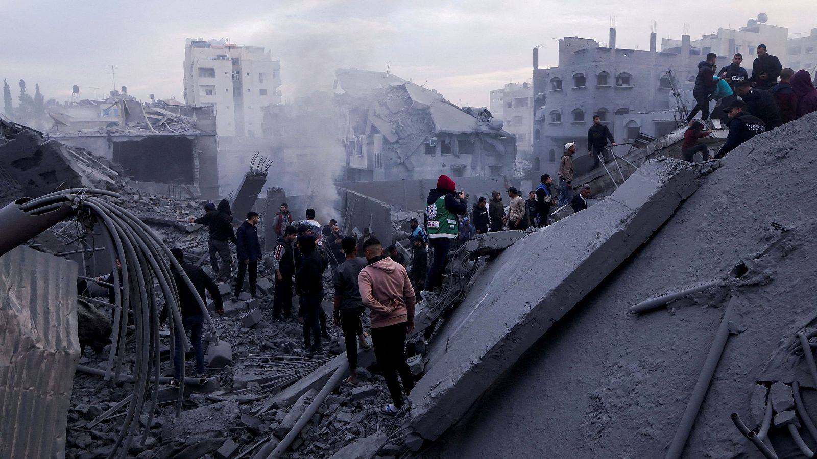 Varias personas caminan entre los escombros de un edificio destruido por los ataques israelíes en Gaza
