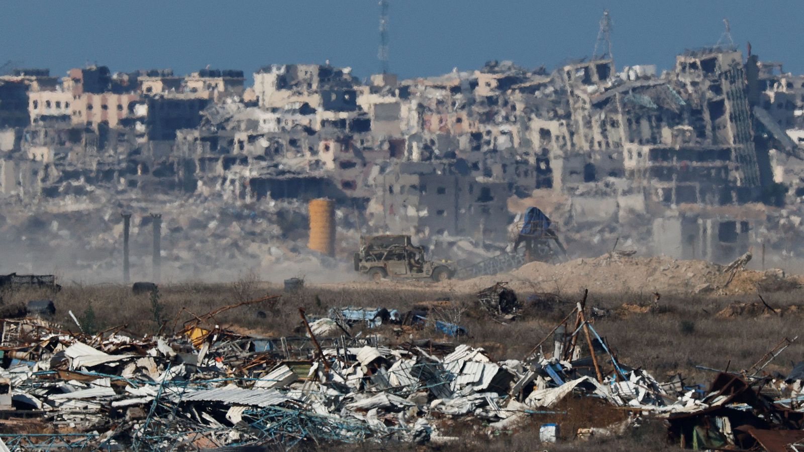 Vehículo militar entre escombros y edificios destruidos en un paisaje desolado.  La imagen muestra la devastación tras un conflicto prolongado.