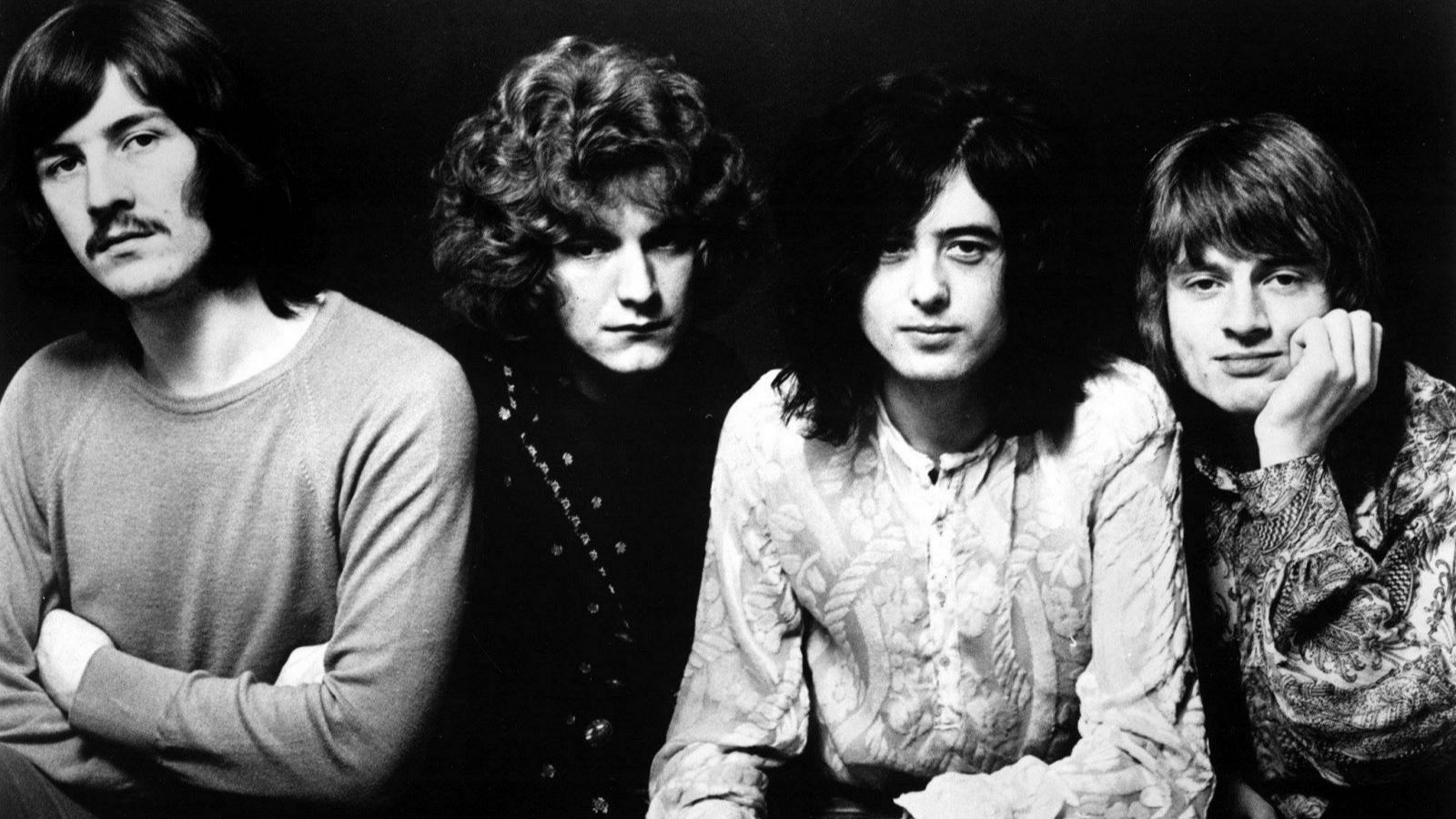 Imagen en blanco y negro de los cuatro integrantes de Led Zeppelin en 1968, mostrando sus estilos de ropa y expresiones faciales serias.