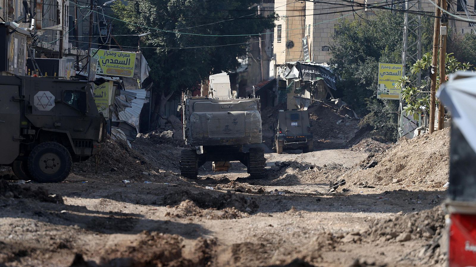 Vehículos del ejército israelí circulan por una carretera dañada cerca de la entrada principal al campo de refugiados de Yenin durante una operación militar israelí, en Cisjordania, el 4 de febrero de 2025.