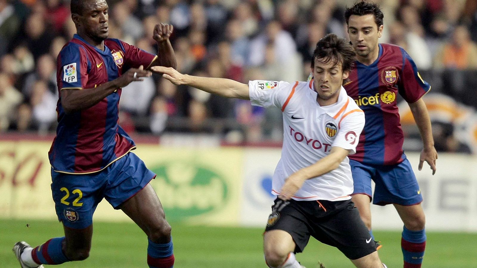 Jugada en un partido de fútbol: dos jugadores persiguen a un rival que controla el balón. Uno de los perseguidores lleva el dorsal 22.