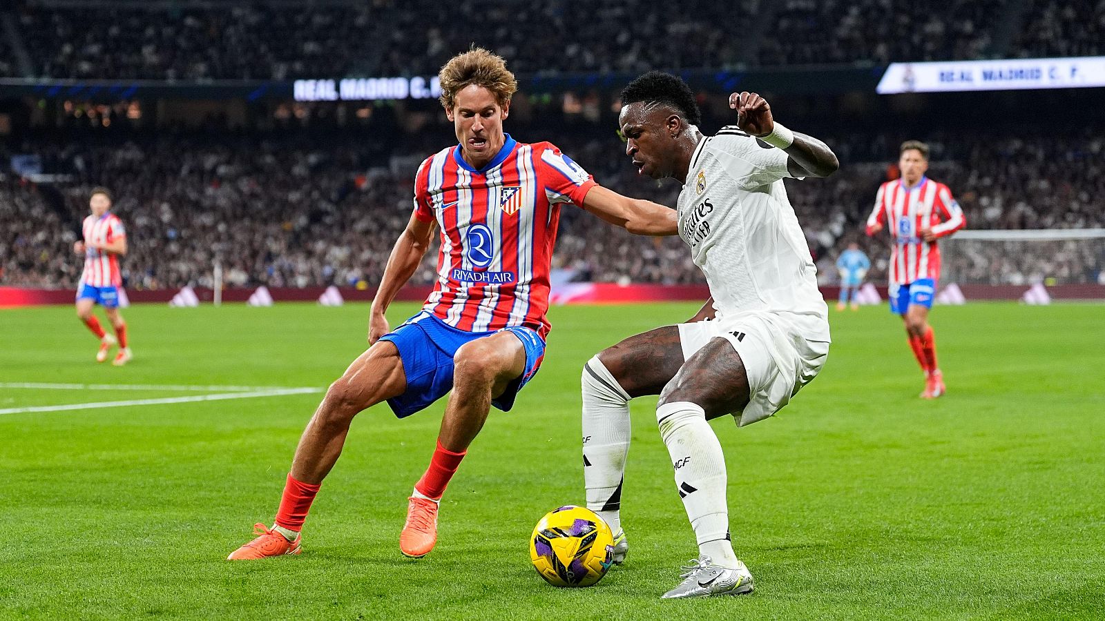 Vinicius (d), ante Marcos Llorente en el Real Madrid - Atlético, el derbi de LaLiga