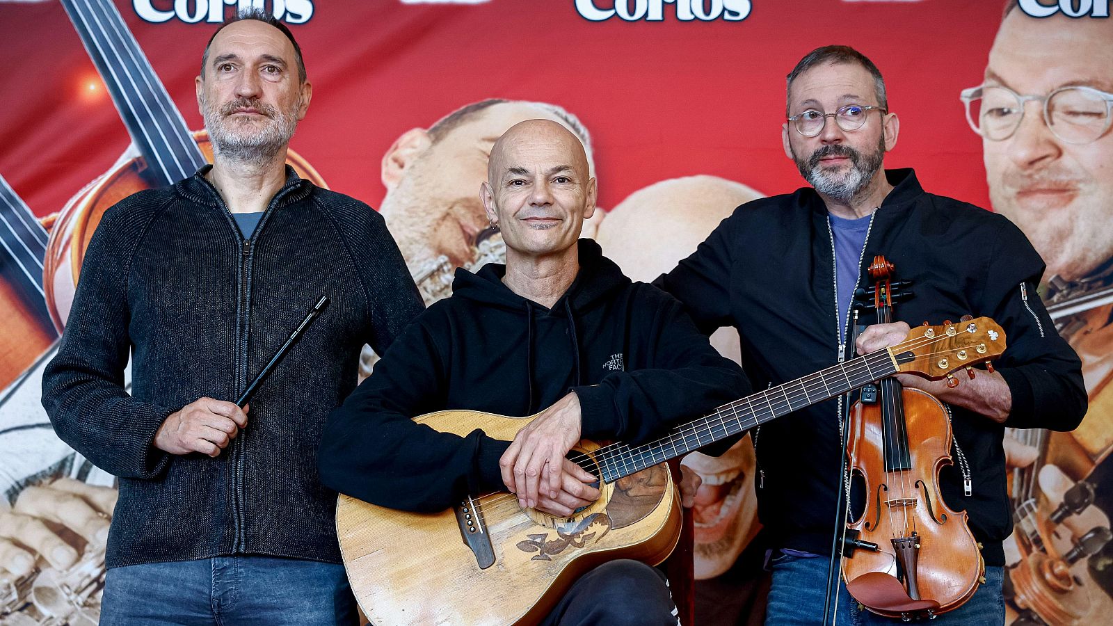 Promoción de la primera gira sinfónica de Celtas Cortos: tres músicos posan con instrumentos (flauta, guitarra, violín) frente a un cartel rojo anunciando el evento.