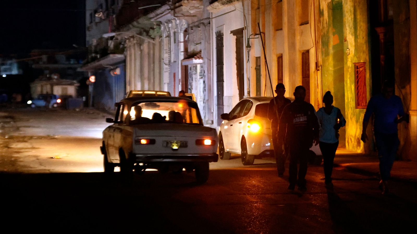 Personas caminan por un sector sin servicio eléctrico en La Habana (Cuba)