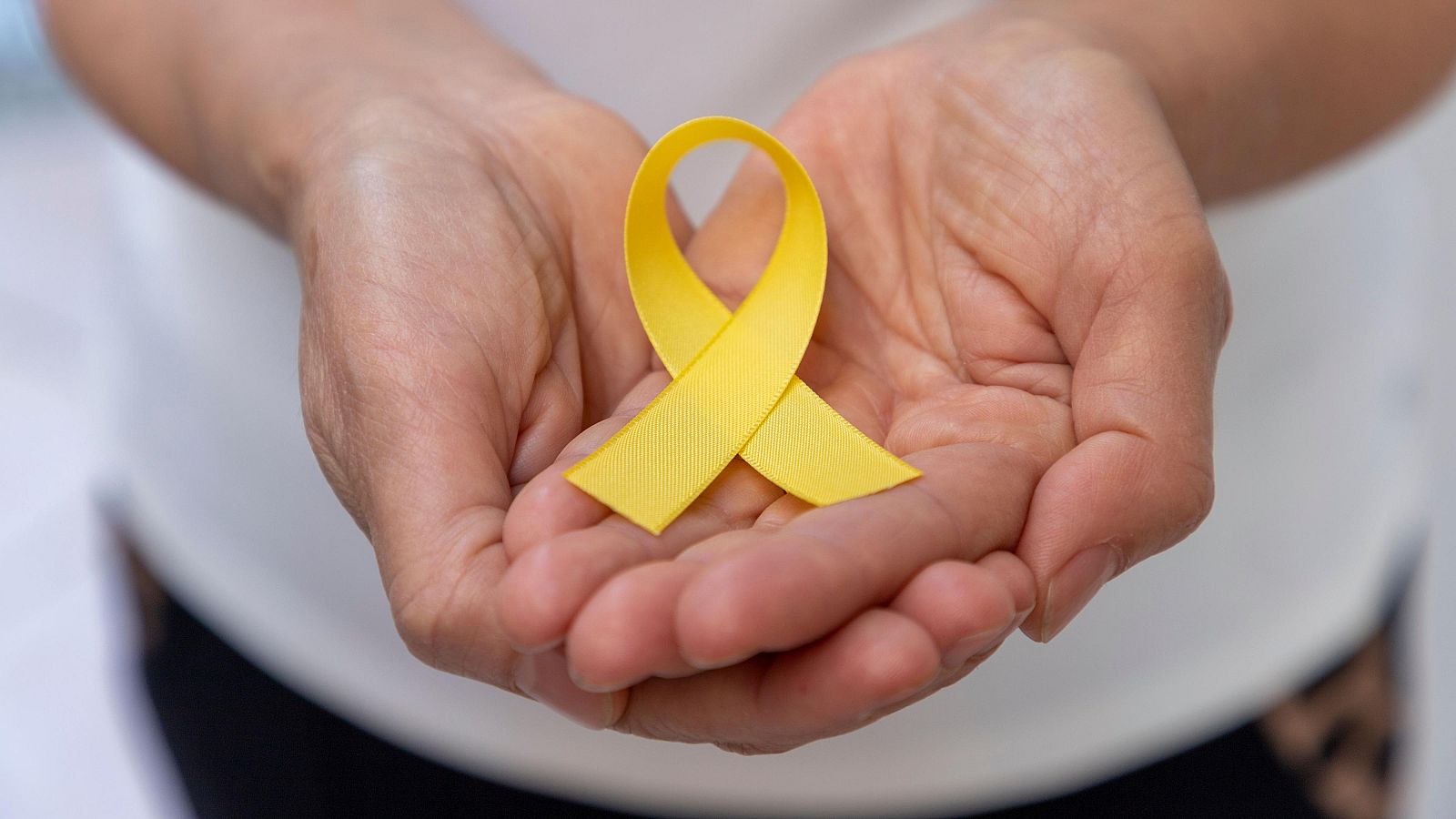 Una persona sostiene un lazo amarillo, símbolo de la prevención del suicidio