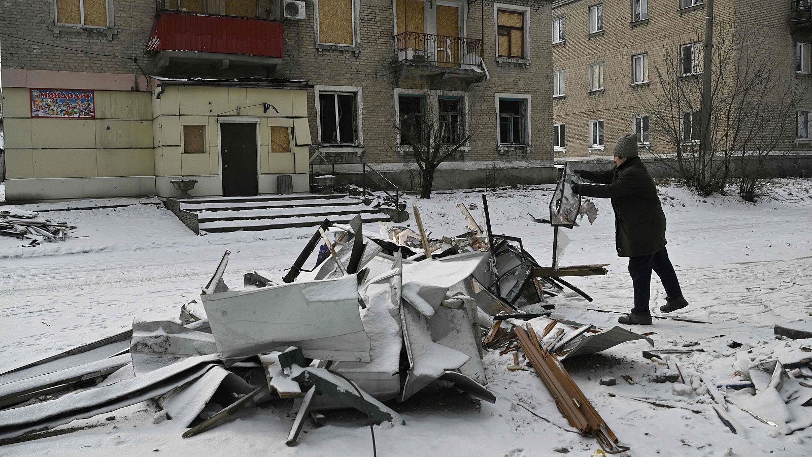 Una mujer ucraniana limpia escombros junto a la Casa de Cultura de Bilytske, dañada tras un ataque ruso, en la región de Donetsk