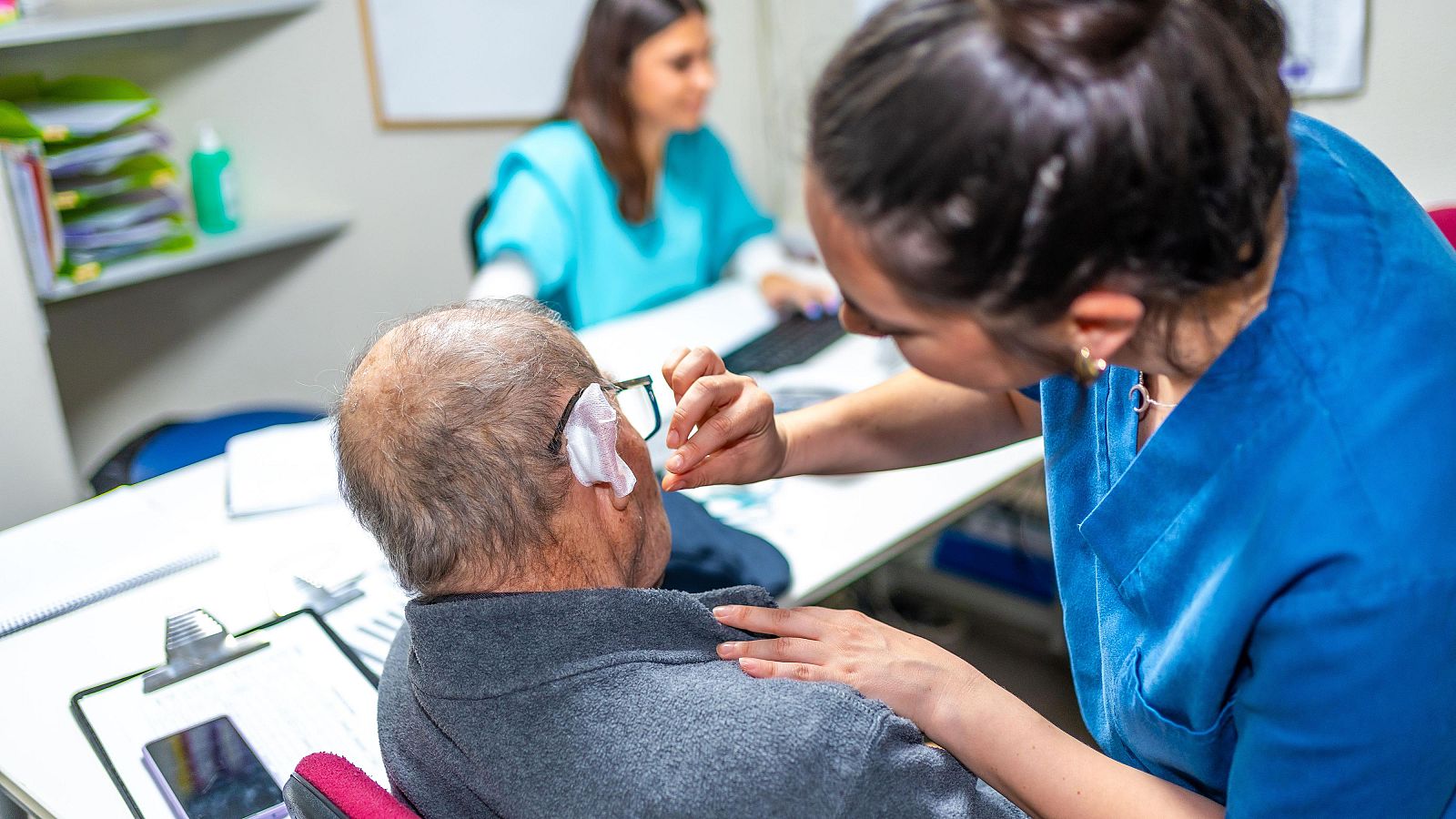 Una enfermera examinando la herida de la oreja de un anciano