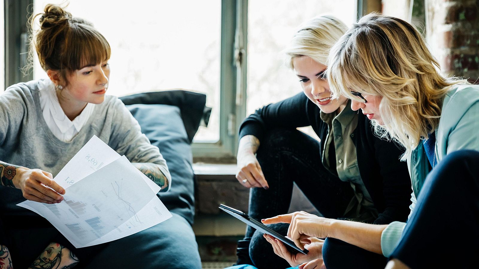 Tres mujeres en una oficina hablando durante una reunión