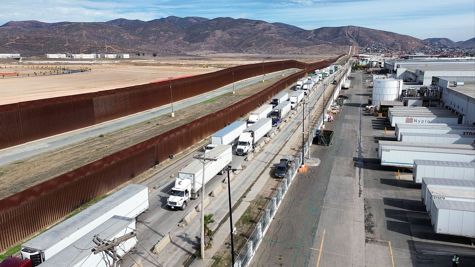 Fotografía aérea donde se observa una fila de vehículos de carga para cruzar una garita hacia EEUU