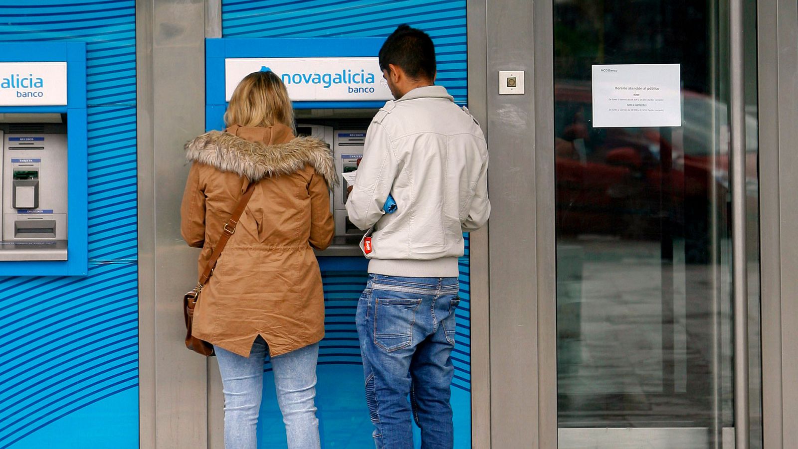 Una pareja saca dinero de un cajero