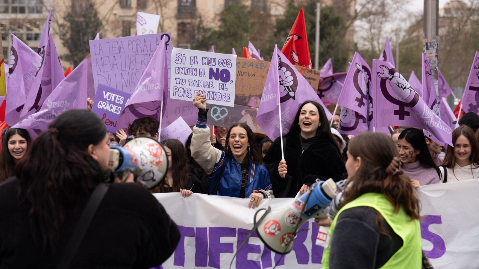 Estudiantes catalanes protestan el Día de la Mujer 2025 con pancartas y megáfonos.  Lema destacado: "Si mi perro entiende el no, tú también puedes entenderlo".