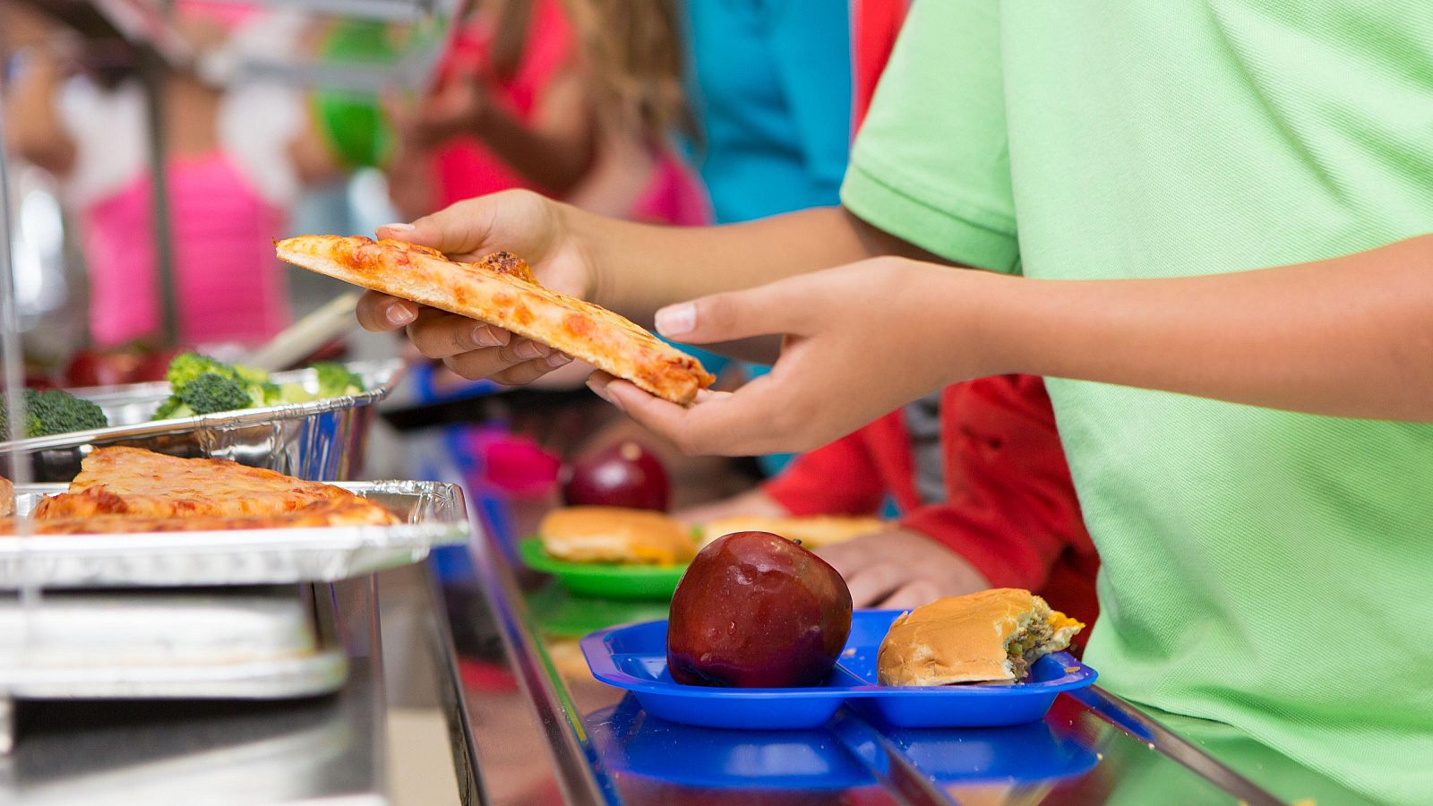 Un niño cogiendo comida en un comedor escolar