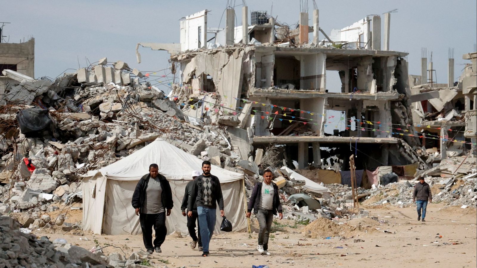 Hombres palestinos caminan cerca de los escombros de las casas destruidas durante la ofensiva israelí, en Rafah, en el sur de la Franja de Gaza, 13 de marzo de 2025.