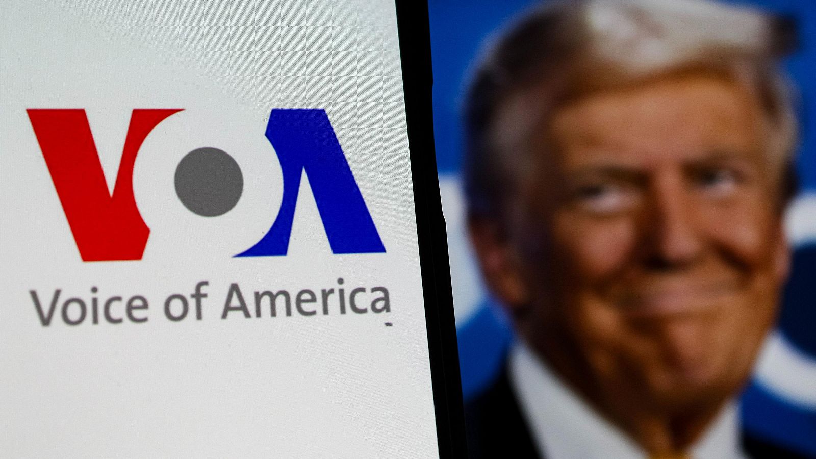 Logotipo de la Voz de América en un teléfono móvil.  Debajo, se lee "Voice of America".  Foto de perfil desenfocada en segundo plano.