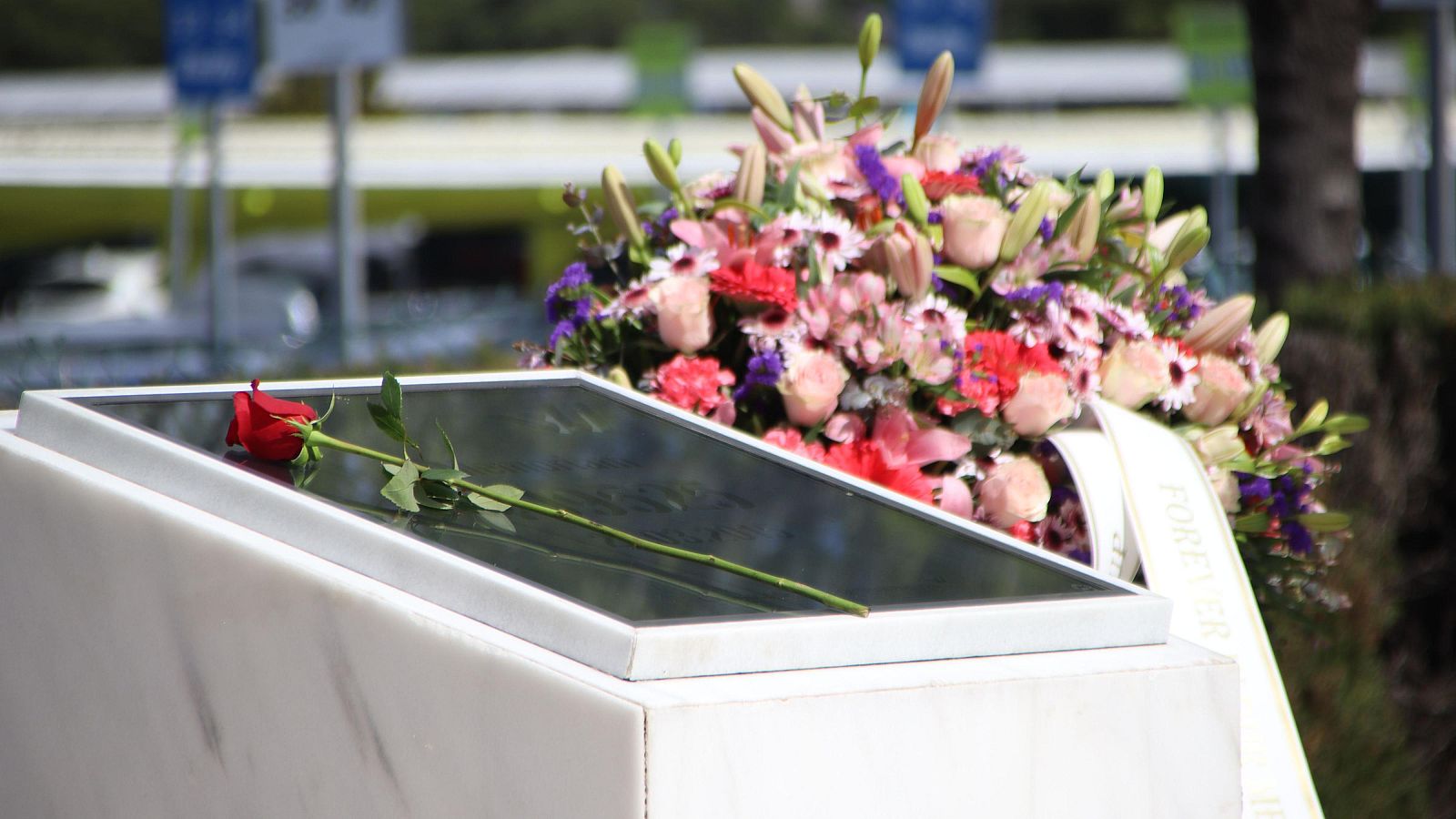 Flors dipositades al voltant de la placa que a l'aeroport del Prat recorda les víctimes de la catàstrofe aèria del 2015 a França