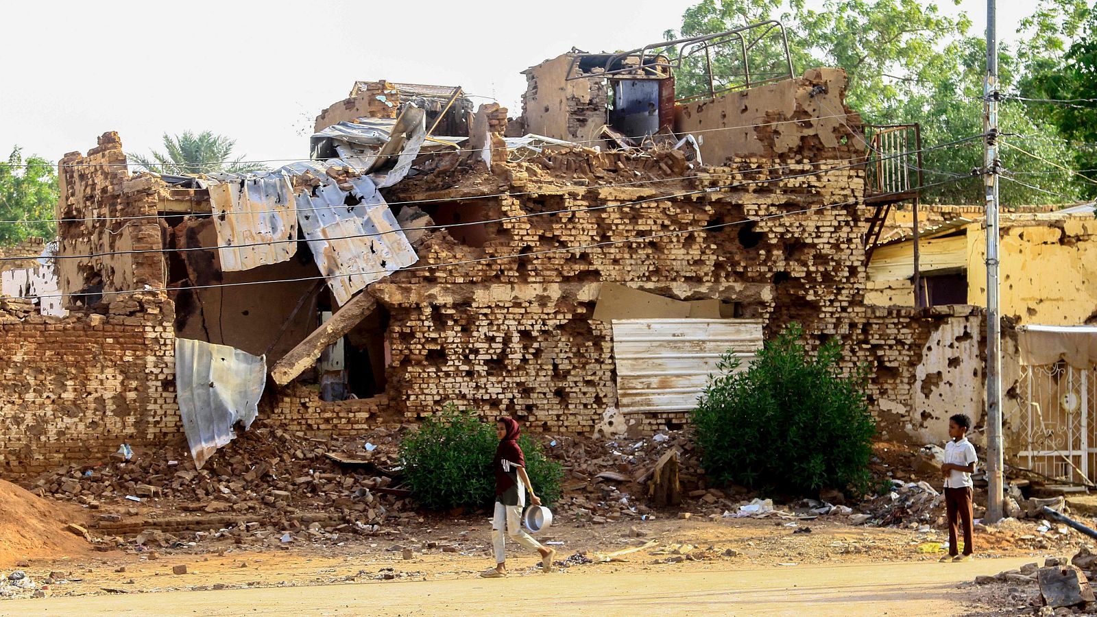 Dos personas pasean junto a un edificio dañado en Omdurman, ciudad gemela de Jartum, el 20 de marzo de 2025.