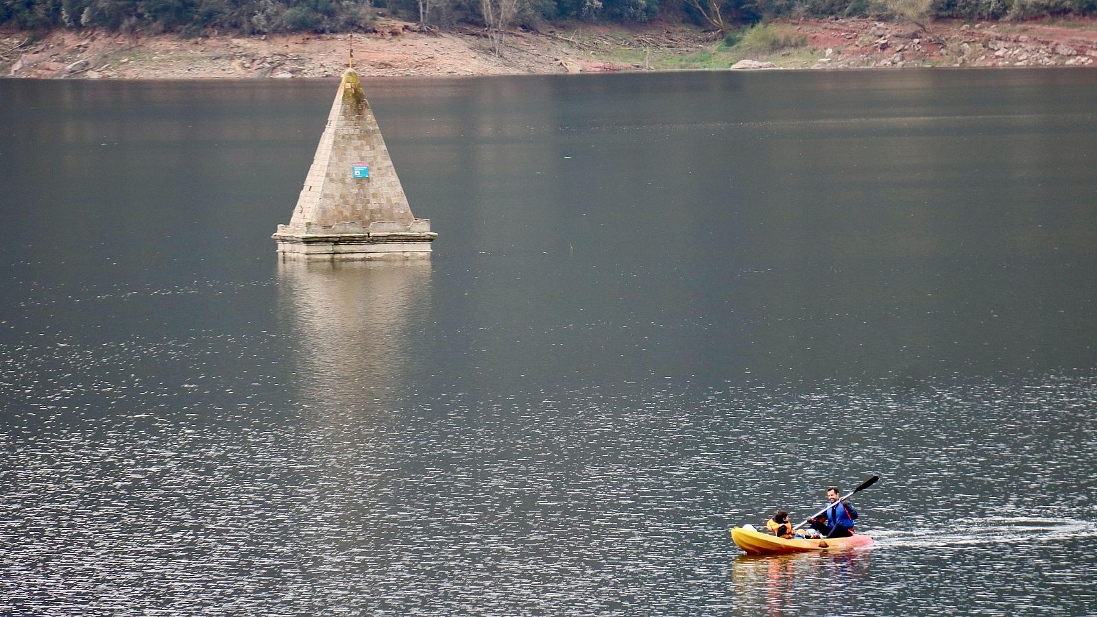 Una barca navega a prop del campanar del pantà de Sau. | ACN