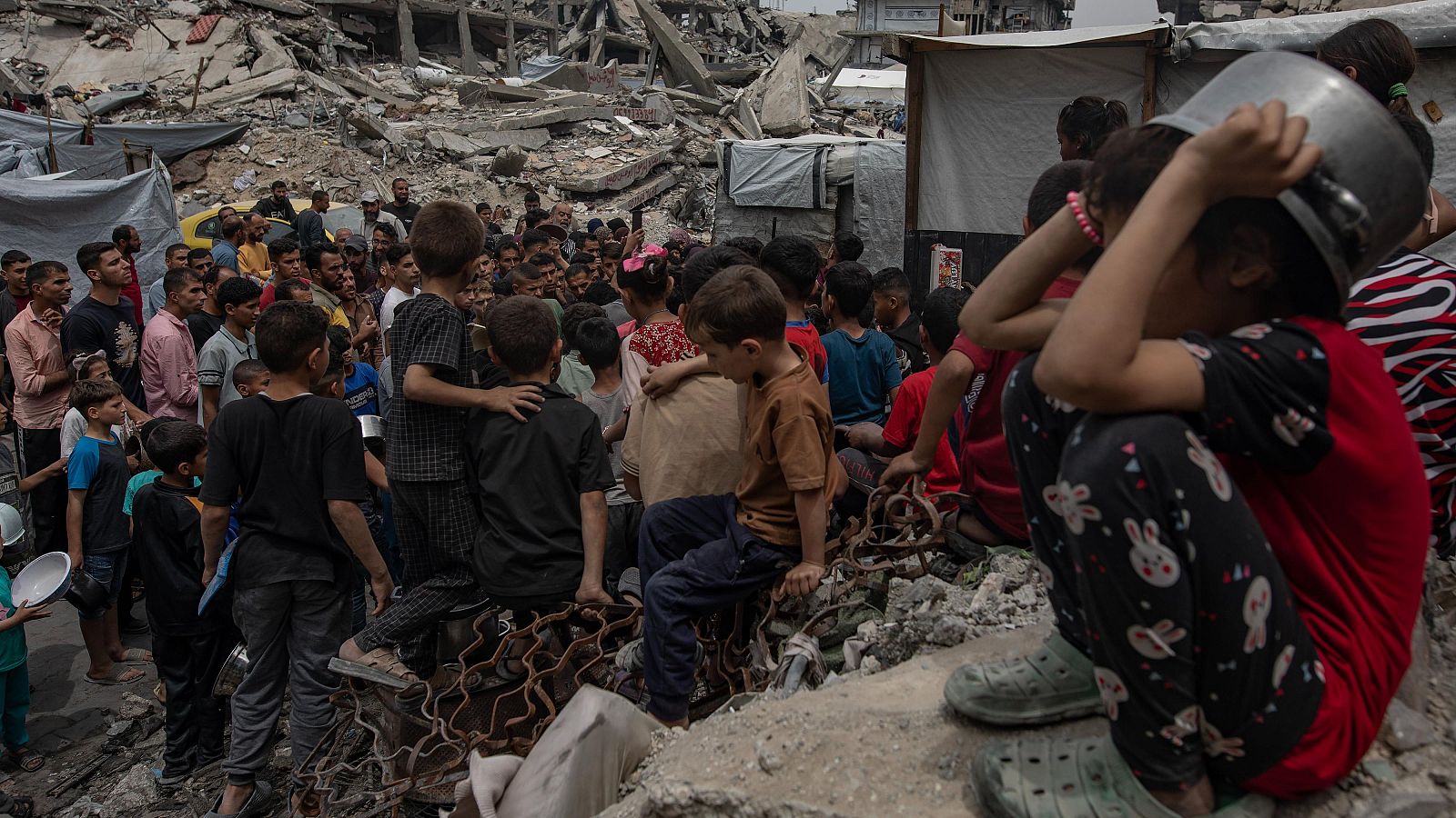 Desplazados internos palestinos se reúnen para recibir una ración de comida de una cocina de caridad, en Jabalia, norte de la Franja de Gaza, 24 de abril de 2025.