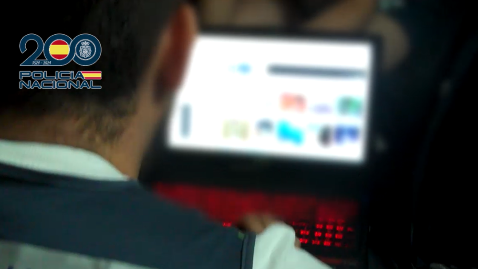 Agente de la Policía Nacional revisa uno de los ordenadores encontrados en el domicilio de uno de los detenidos