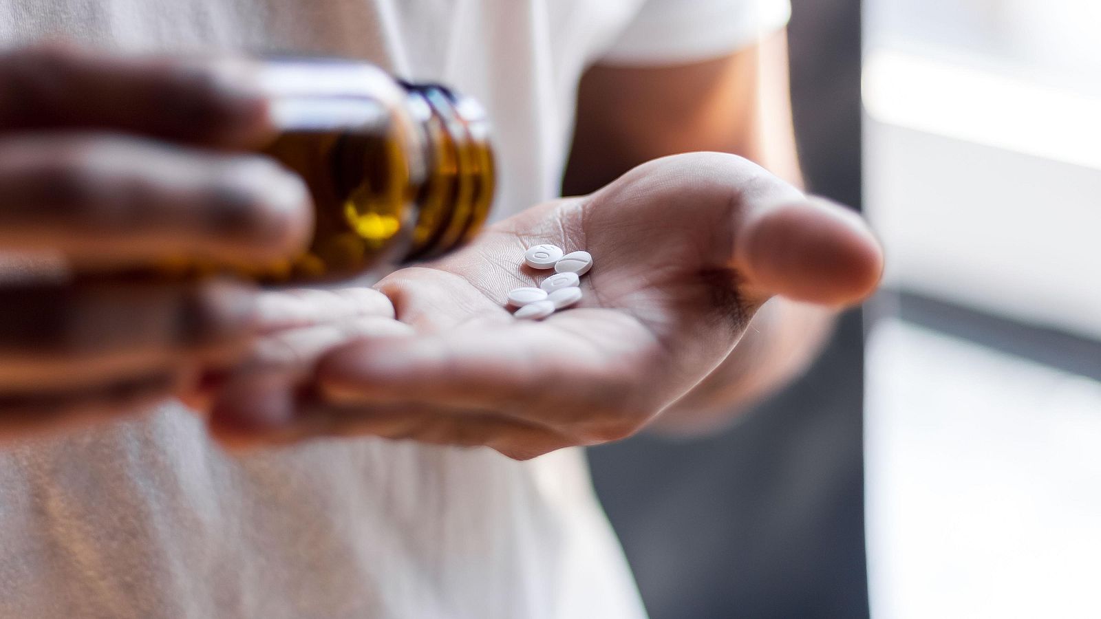 Una persona saca pastillas de un bote en una imagen de archivo