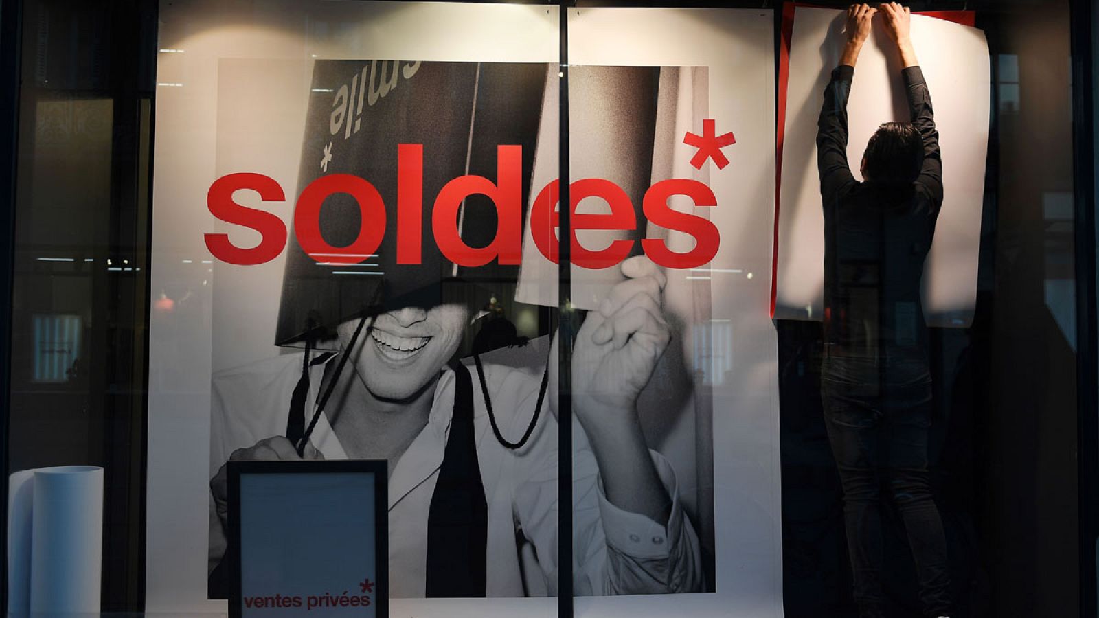 Un empleado cuelga un cartel de rebajas en Estrasburgo